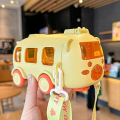 Yellow toy bus held by a hand in an indoor setting