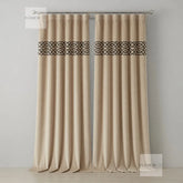 Pair of beige curtains with decorative black bands on a gray background