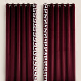 Pair of burgundy curtains with Greek key pattern on a white background