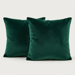 Two green velvet pillows on a light gray background
