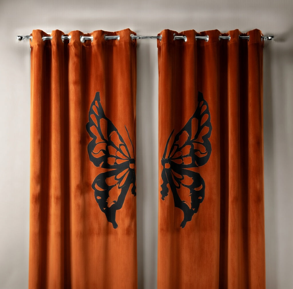 Orange curtains with black butterfly designs on a beige wall.