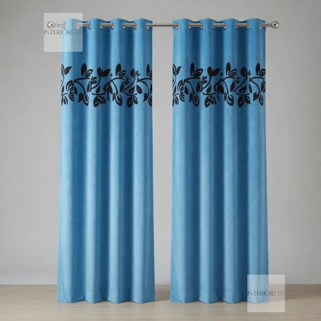 Pair of sky blue curtains with black leaf pattern on a neutral background
