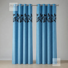 Pair of sky blue curtains with black leaf pattern on a neutral background