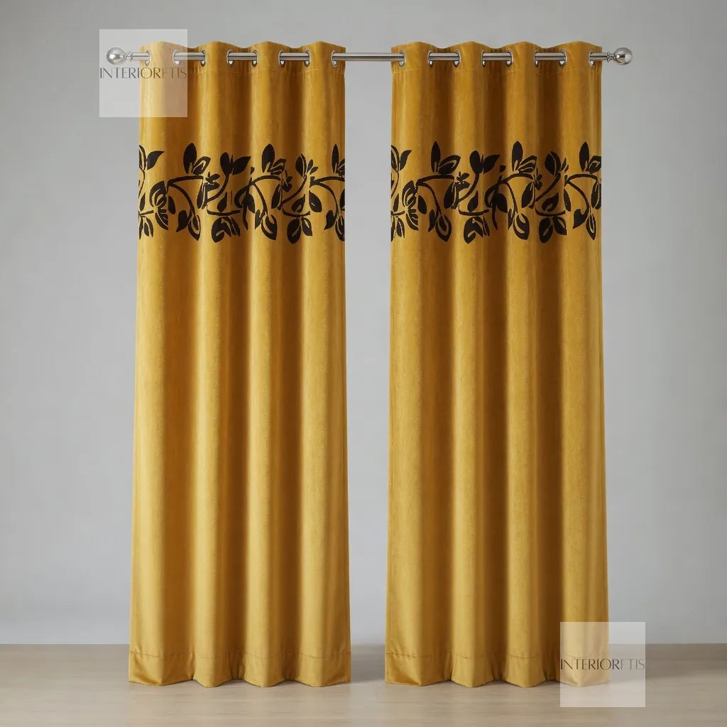 Pair of mustard yellow curtains with black leaf patterns on a gray background