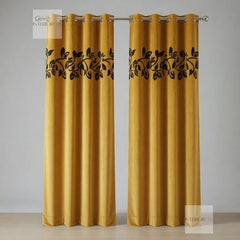Pair of mustard yellow curtains with black leaf patterns on a gray background