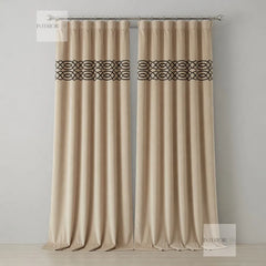 Pair of beige curtains with decorative black bands on a gray background