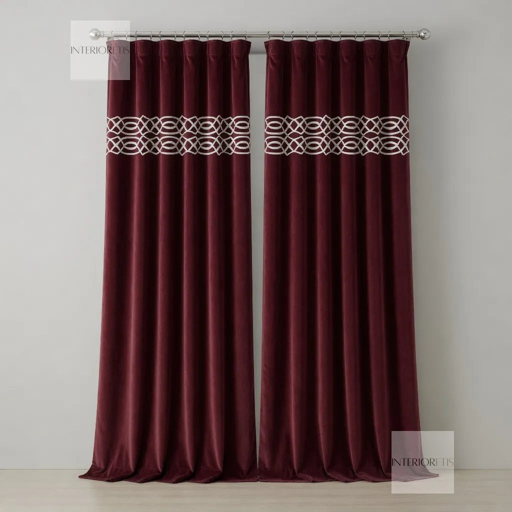 Pair of maroon curtains with a decorative band on a plain background