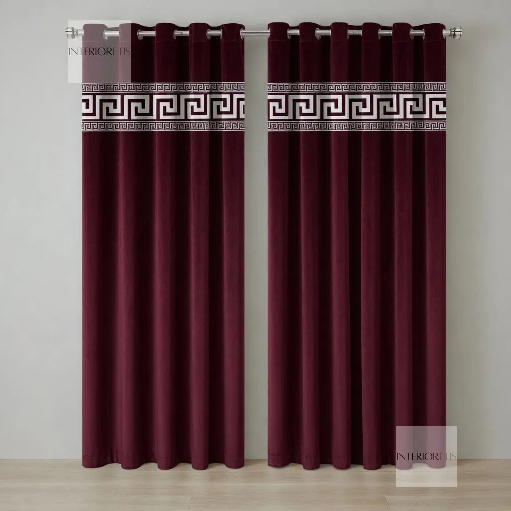 Pair of maroon curtains with decorative banding on a neutral background