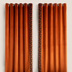 Pair of orange curtains with a black geometric pattern on a white background