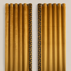 Pair of mustard yellow curtains with decorative black patterns on a beige background