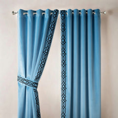 Pair of blue curtains with decorative trim on a beige background