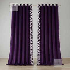 Pair of purple curtains with white geometric patterns on a wooden floor and light gray wall.