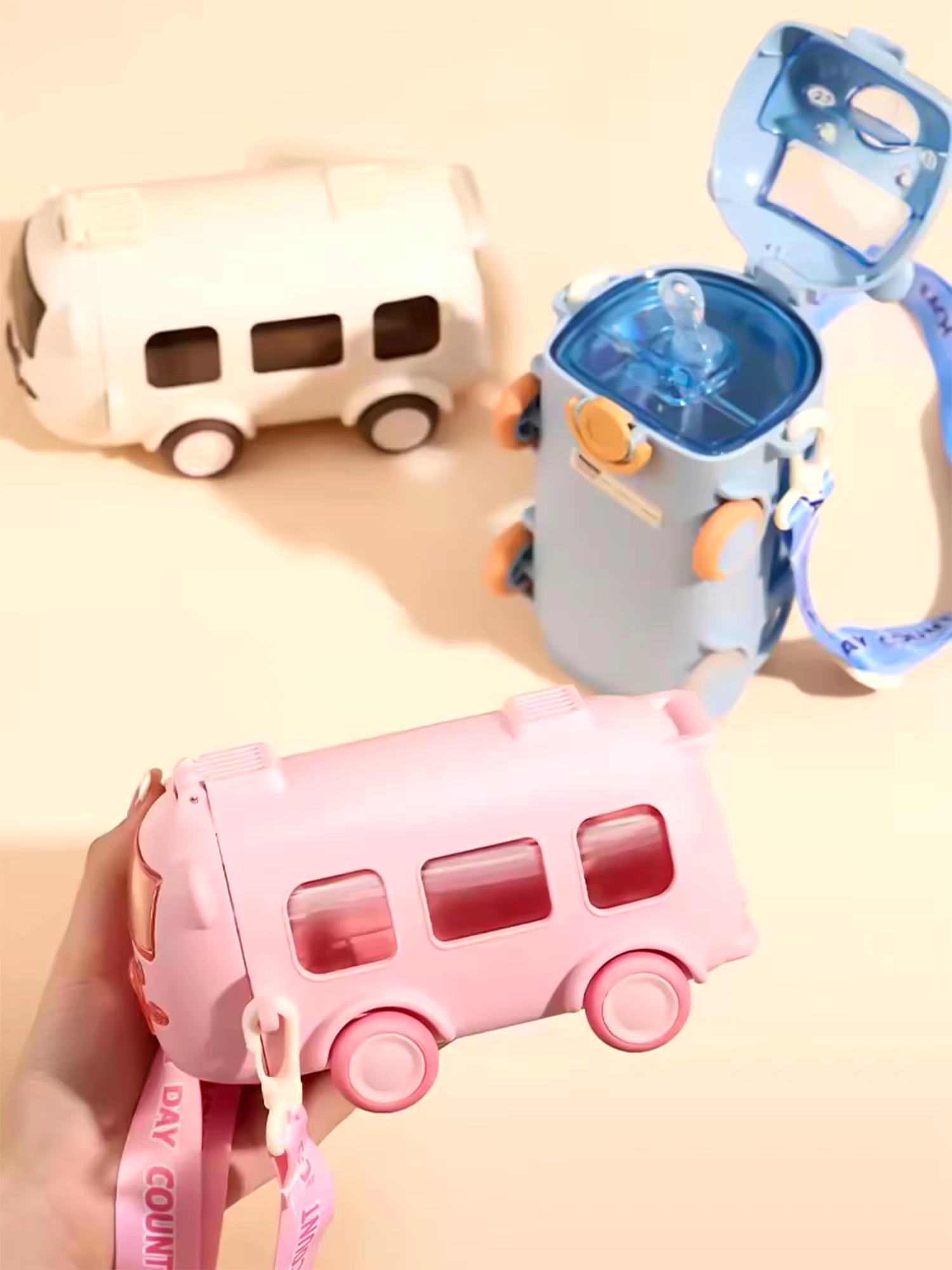Pink bus-shaped water bottle with a matching car-shaped container on a light pink background